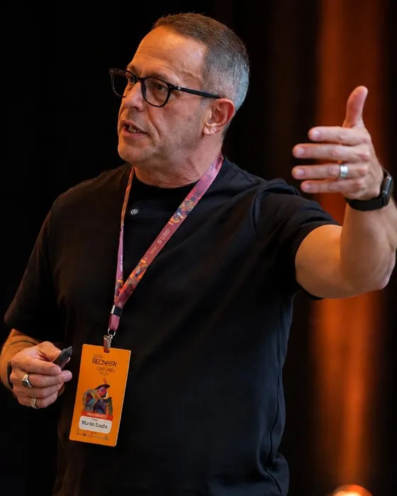 Murilo Souto, fundador da ide.IA, em palco no Rec'n'Play Caruaru 2026, com o crachá do evento